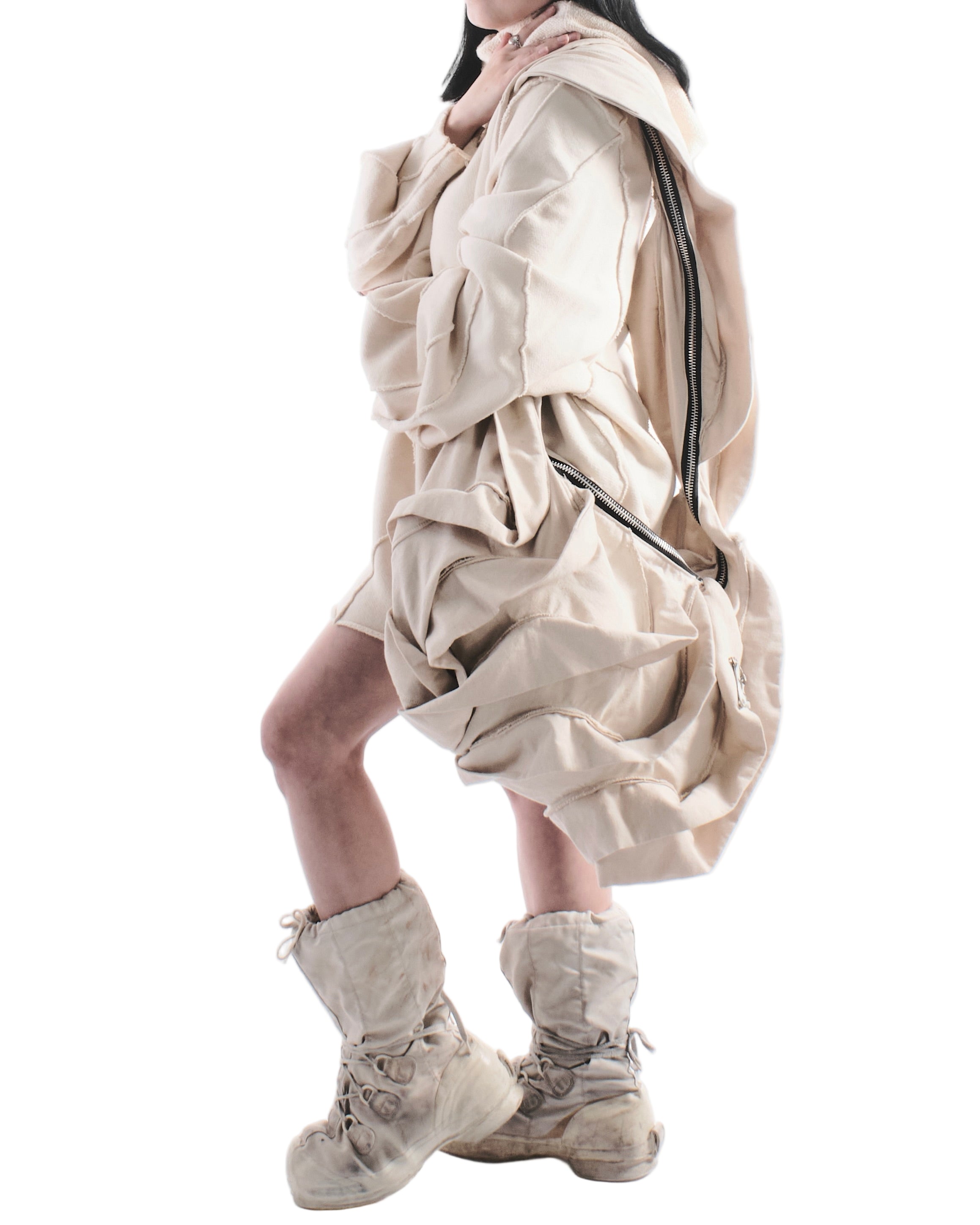 Person wearing a large beige coat with a hood on a white background