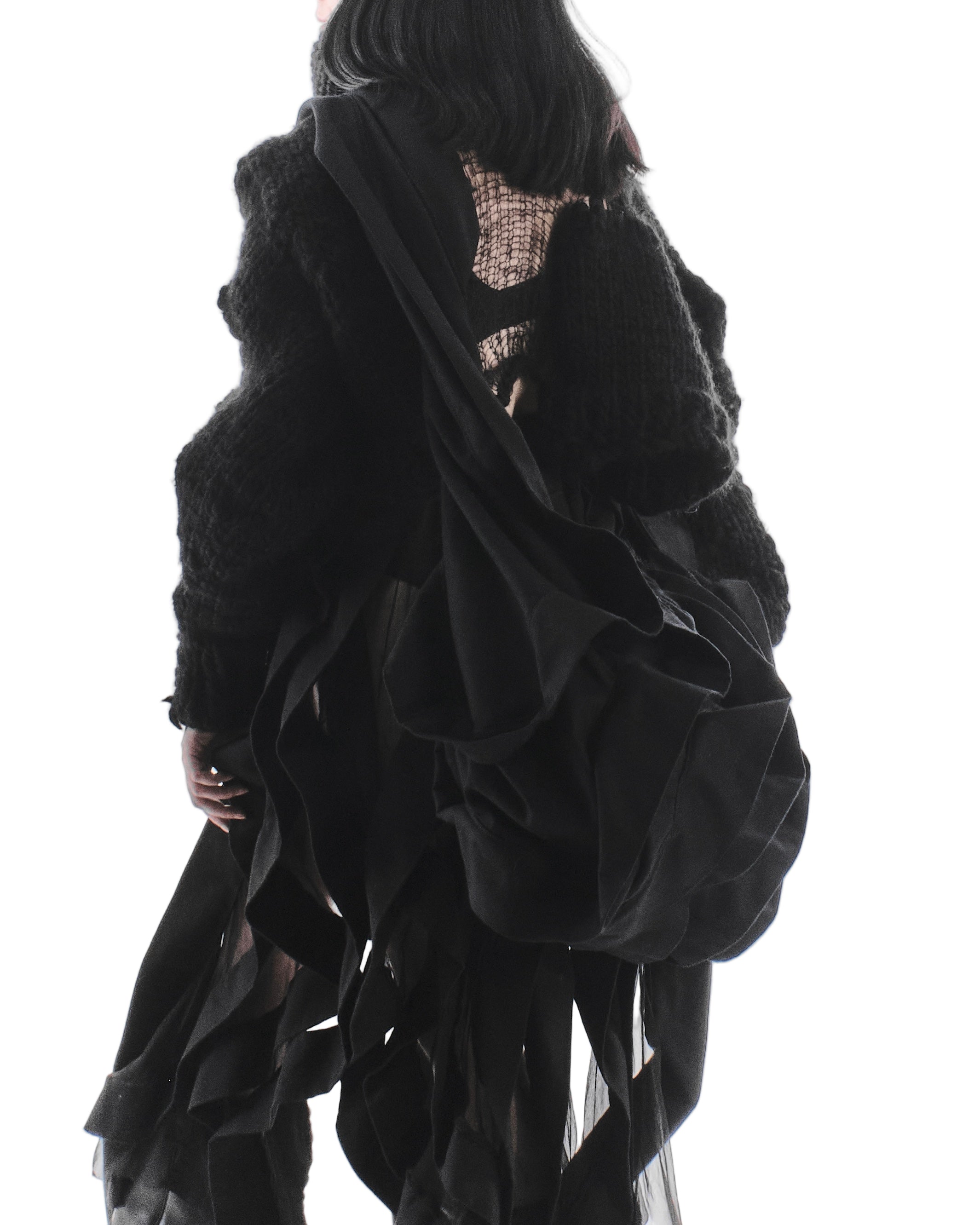 Black textured garment with sheer overlay on a white background