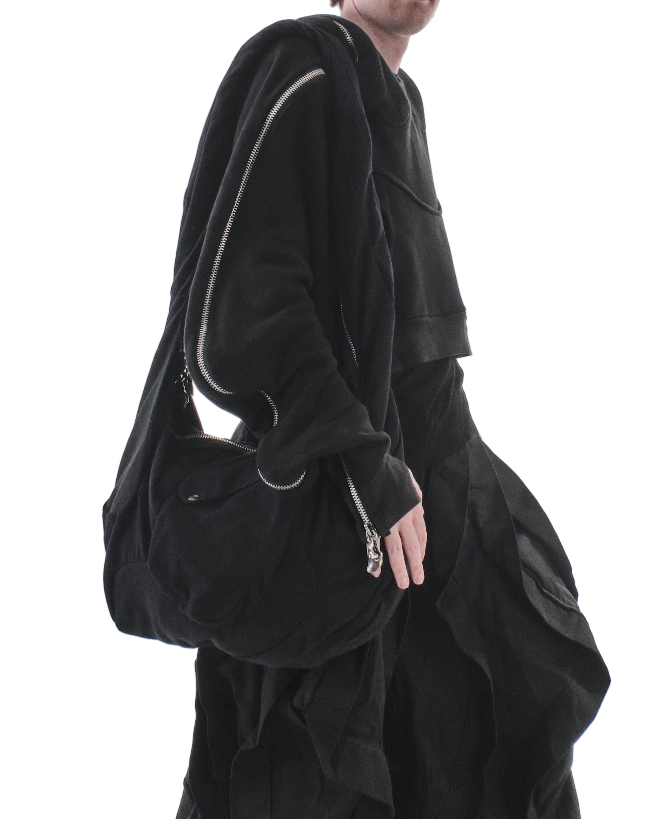 Person wearing a black outfit with a large bag on a white background