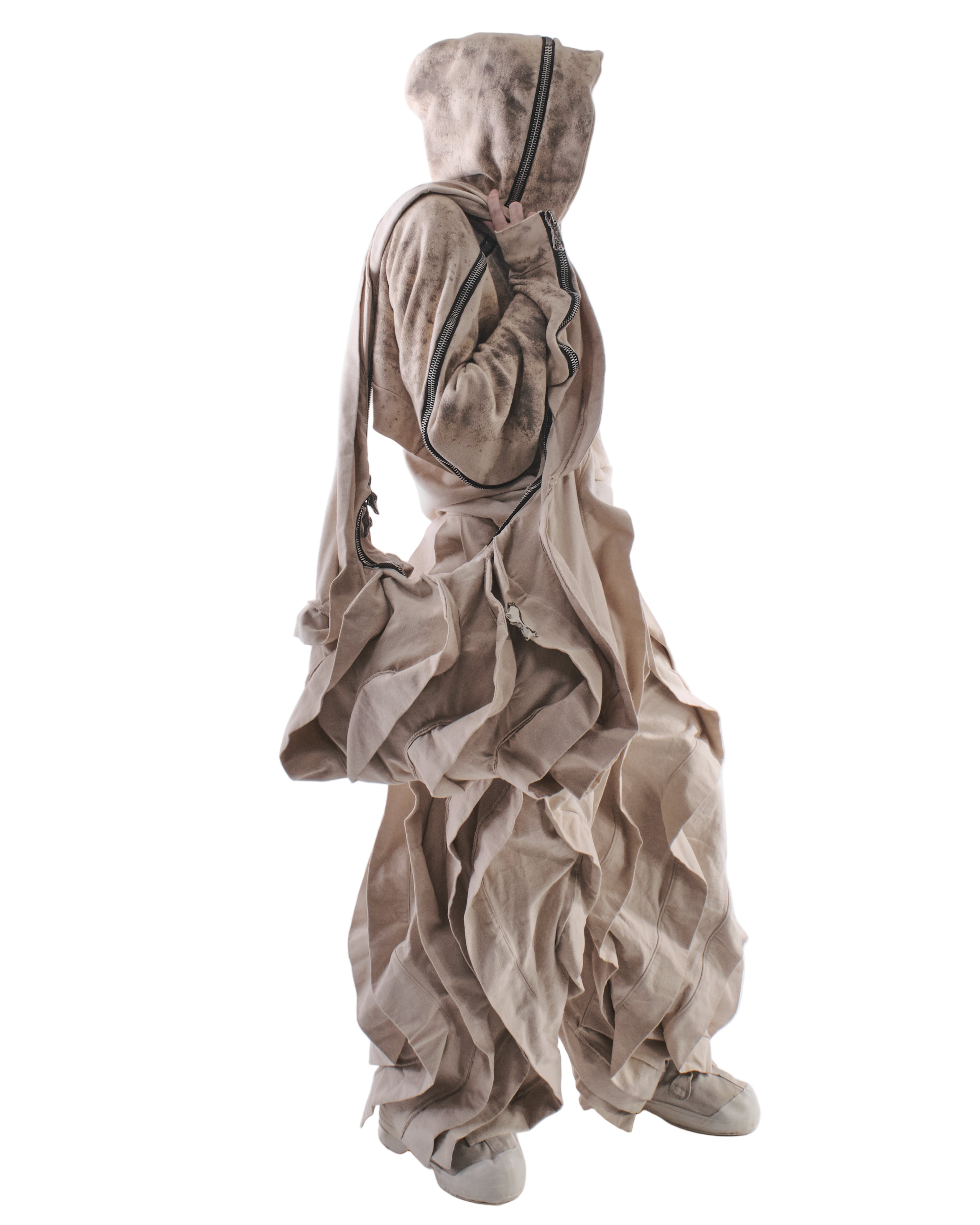 Person wearing a large, beige, baggy outfit on a white background