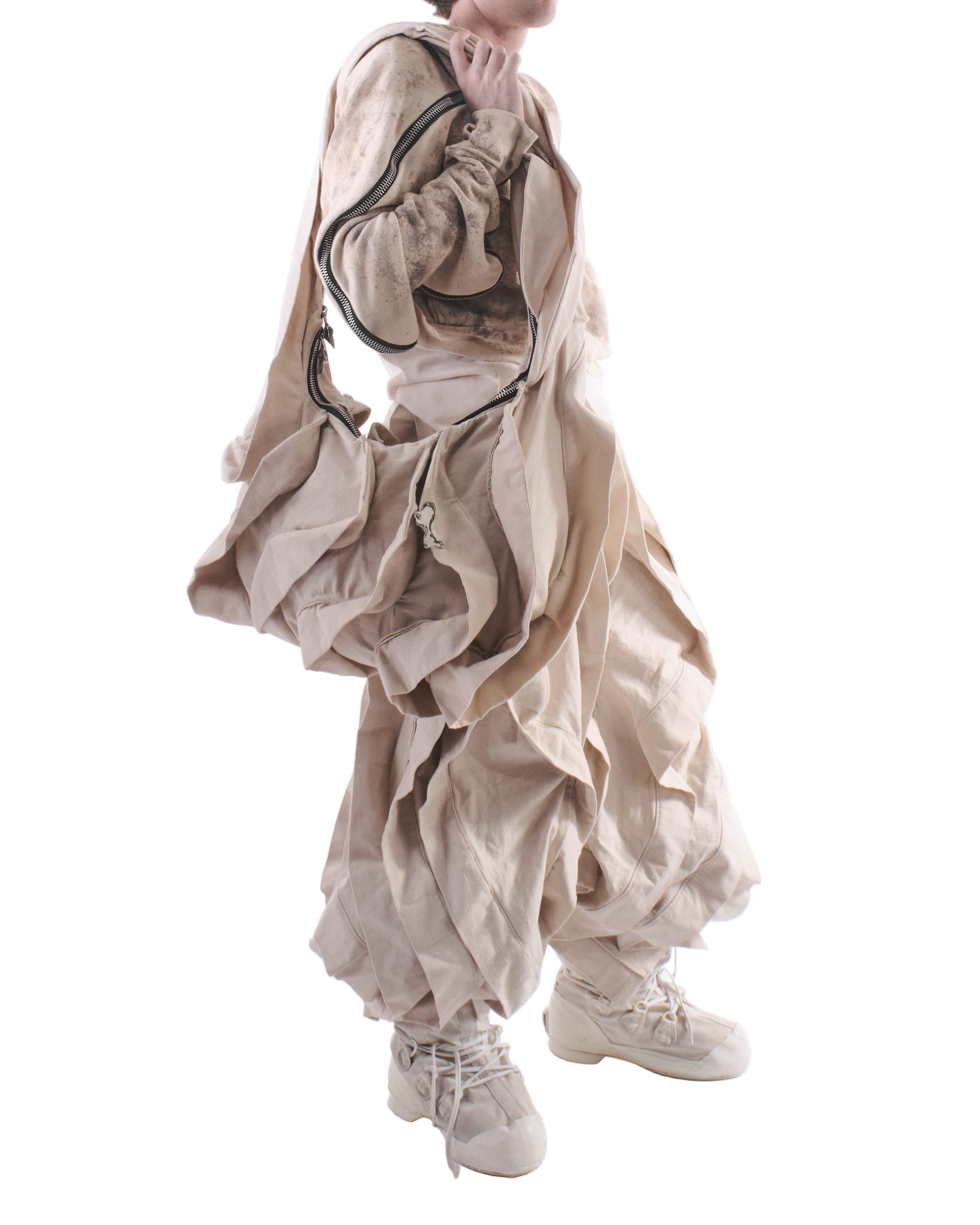 Person wearing a beige layered outfit with ruffles on a white background