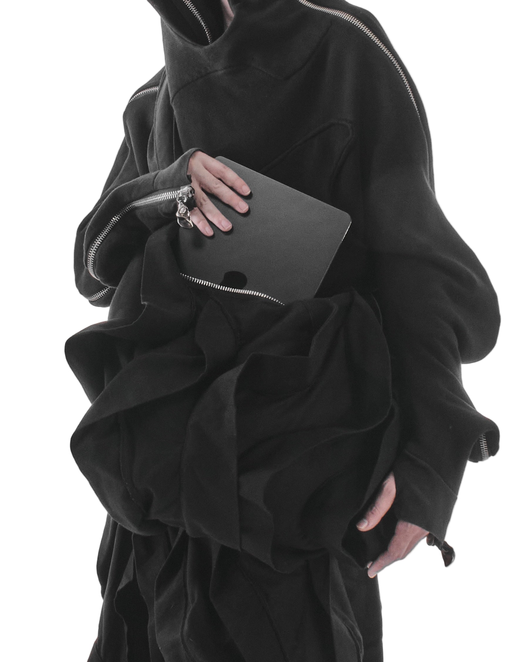 Person wearing a black outfit holding a black laptop on a white background